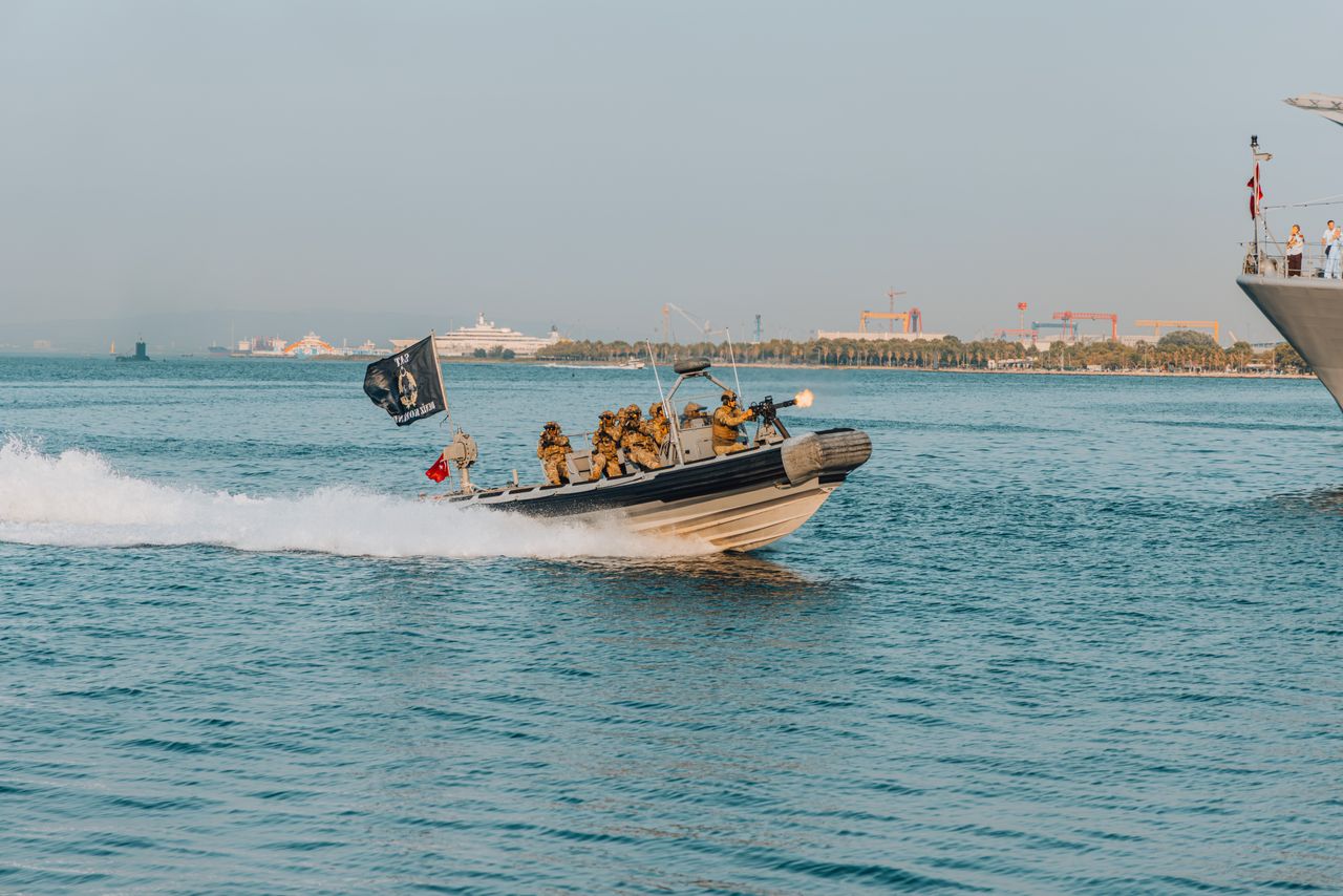 Soldiers on a speedboat executing military tactics during a naval demonstration. Perfect for defense themes.