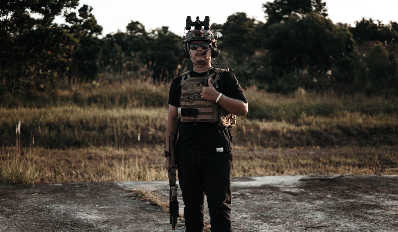 A soldier standing outdoors wearing tactical gear and holding a rifle, showcasing military readiness.